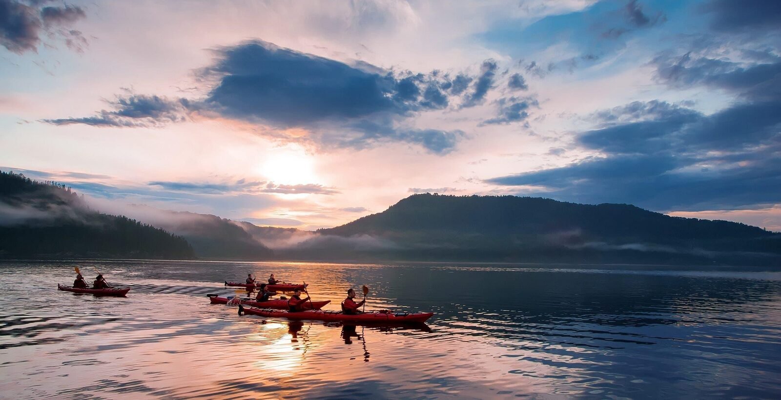 Group kayaking on a calm lake at dusk