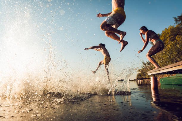 Friends jumping into a lake for a cold-water plunge